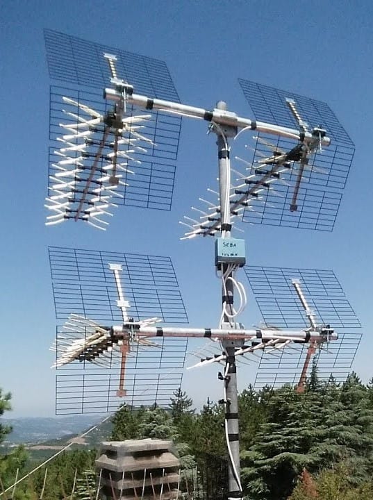 Antenna parabolica su sfondo di alberi e cielo azzurro